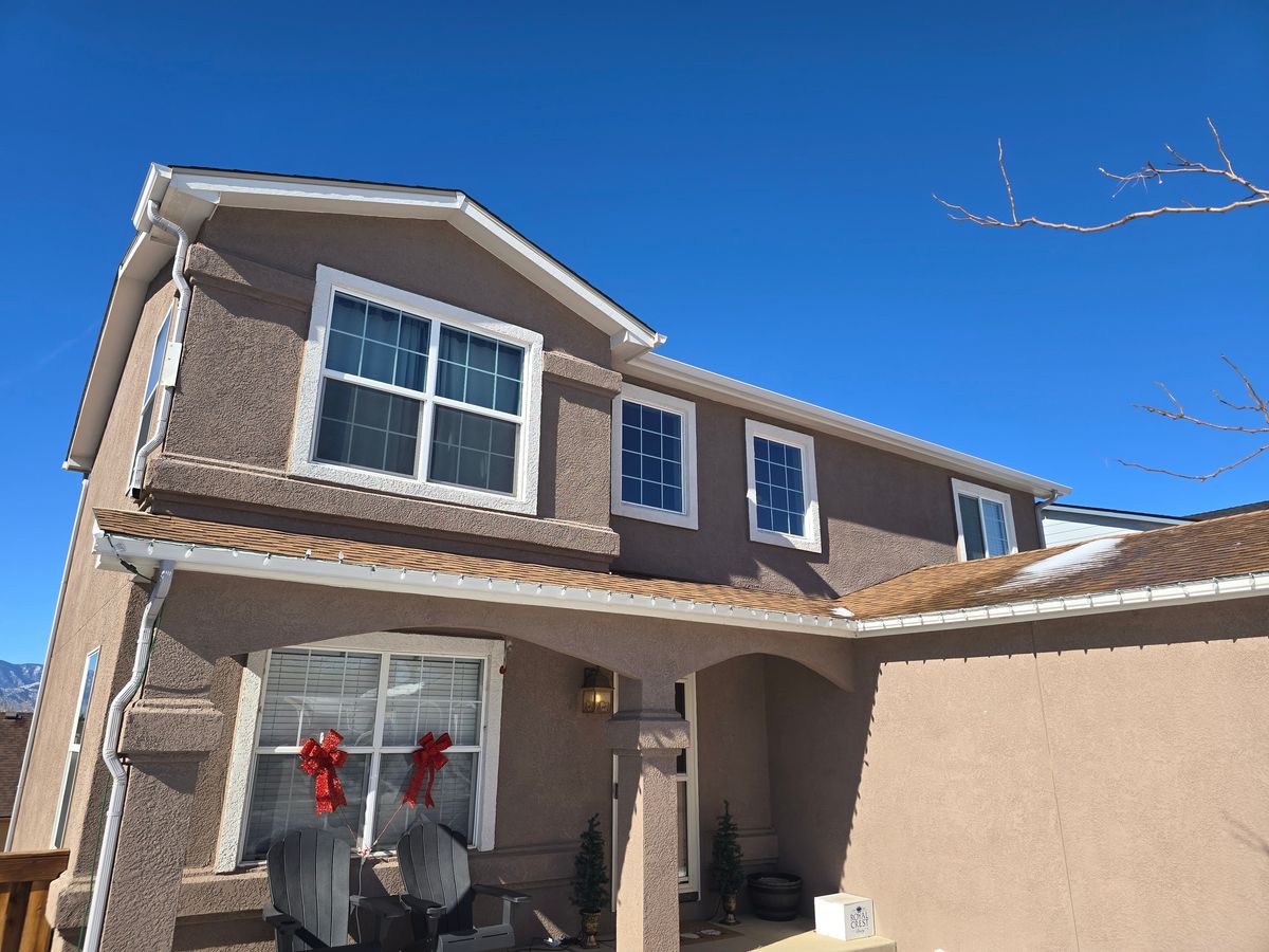 Tan two-story house with a new shingle roof above the front entry