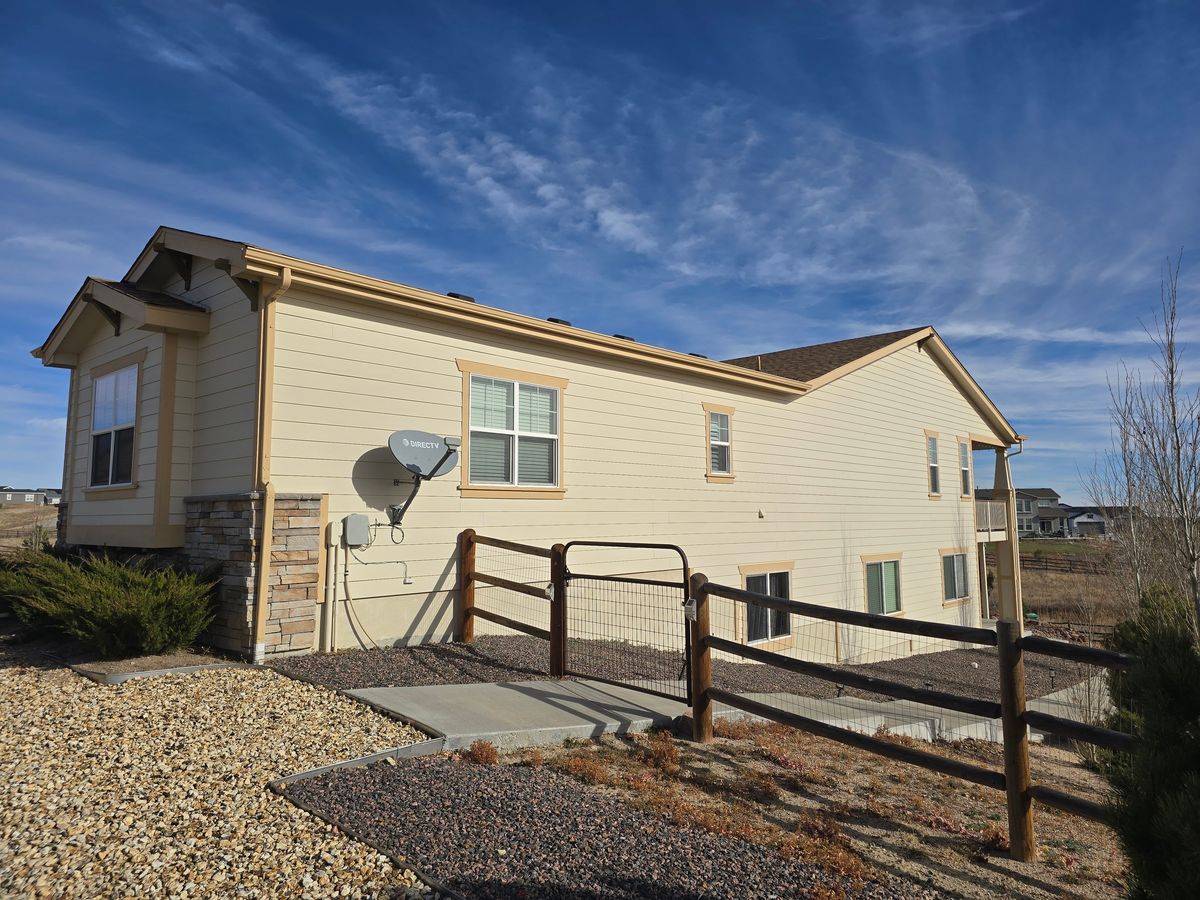 Tan single-story house behind a split-rail fence with a new shingle roof