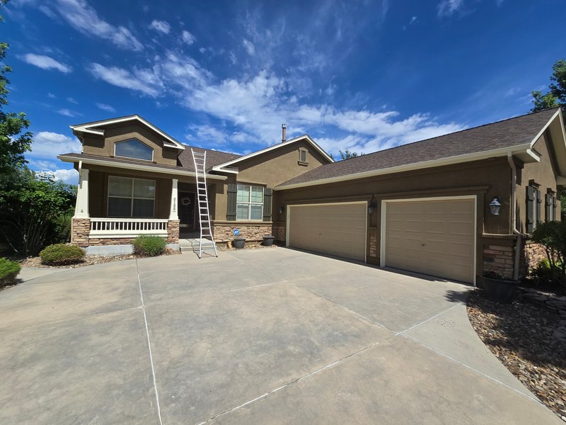 Tan ranch house with visible gutters and a ladder at the roof edge