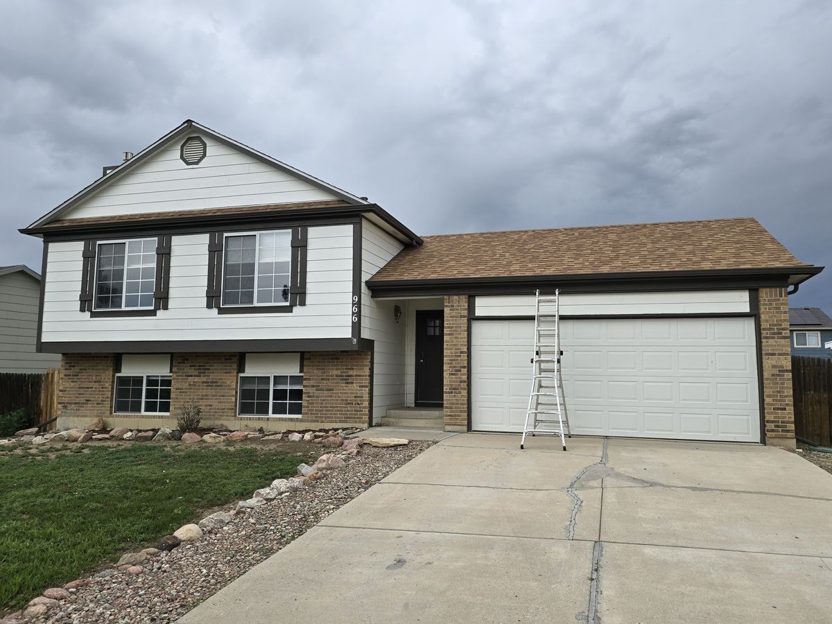 White and tan house with a ladder up to the roof