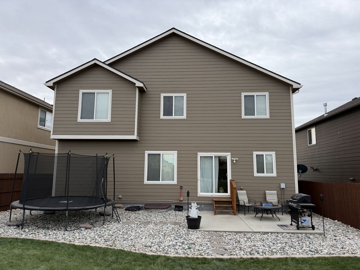 Rear elevation of a tan two-story house with a patio and a trampoline