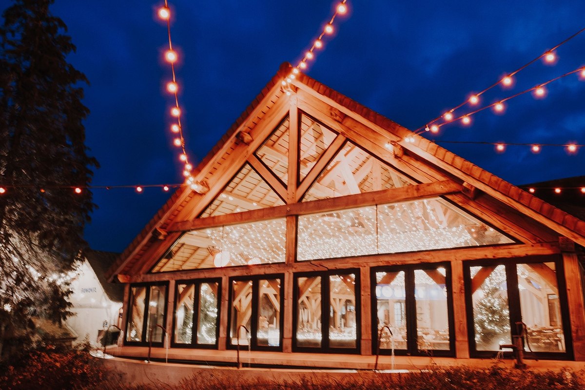 Gabled building at dusk with strings of warm bulb lights running from its roof peak