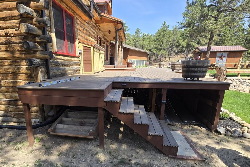 Log home deck with freshly stained boards and timber stairs