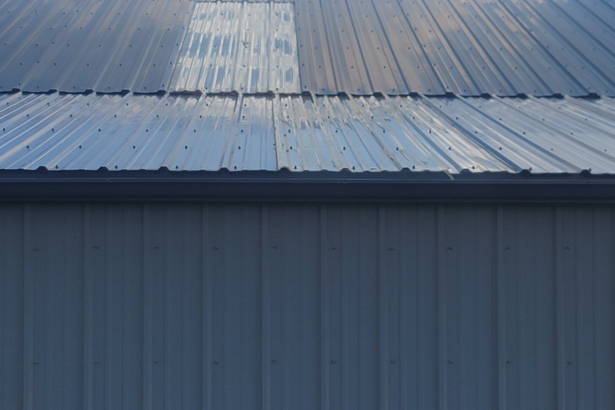 Close view of light-colored metal roof panels below a blue sky